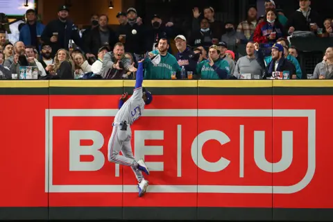 Abbie Parr Adolis Garcia of the Texas Rangers takes a home run away from Mitch Haniger of the Seattle Mariners