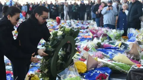 Getty Images Aiyawatt Srivaddhanaprabha and the club owner's wife Aimon Srivaddhanaprabha lay a wreath at the tributes to the victims of the crash at Leicester City Football Club's King Power Stadium