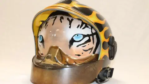A fire helmet with a visor painted to look like a tiger looking directly at camera