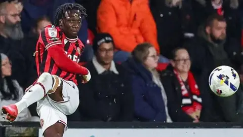 Walsall's Vincent Harper aims a left-footed pass across the field and watches the ball fly away in his follow through