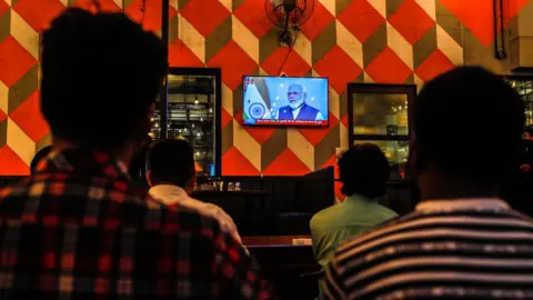 EPA People watch a live address by Indian Prime Minister Narendra Modi after the government scrap Article 370, at a restaurant in Mumbai, India, 08 August 2019