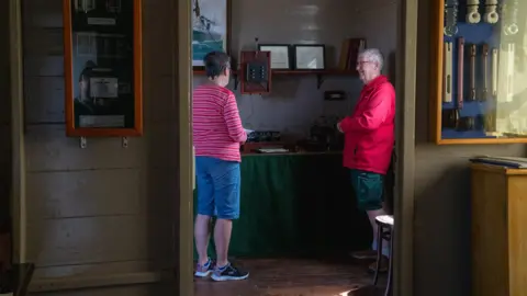 National Trust Geoff Bate is standing inside the station speaking to someone who has come to look at the equipment.