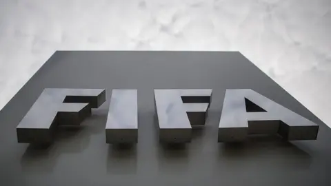 A picture of a sign outside the headquarters of football's world governing body Fifa, spelling out Fifa in capital letters against a grey backing and a cloudy sky