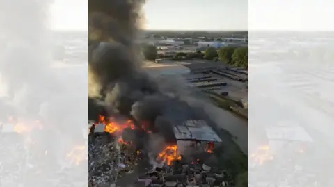 Michael Myers A fire at what looks like a scrapyard - with piles of burning rubbish and several buildings ablaze.