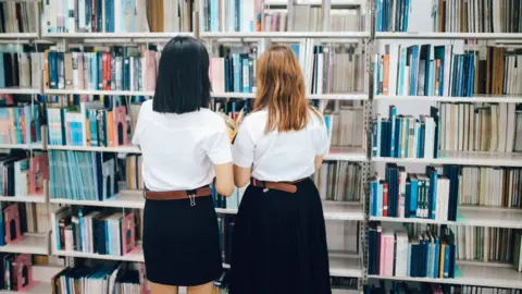 Getty Images Two female students searching for books in a library - stock photo