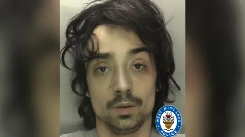 Diogo Bettencourt pictured in a mugshot with messy black hair and black stubble and moustache.