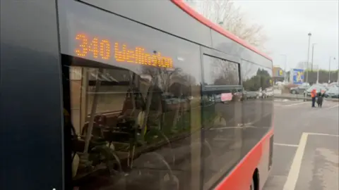 The side of a red bus with a digital board saying 340 Wellington 