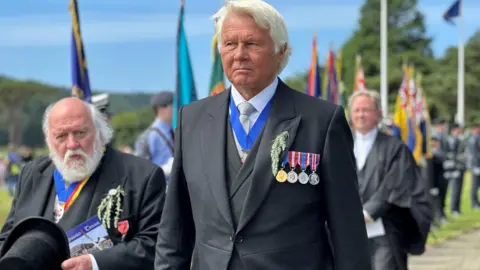 Peter Kelly and Allen Corlett wearing black suits with the Captain of the Parish medals around their necks.