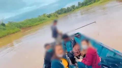 NOPPORN WICHACHAT An image of crossing a river with a victim rescued by Thai authorities.