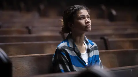 HBO Zendaya sitting in a church pew as Rue in a still from Euphoria