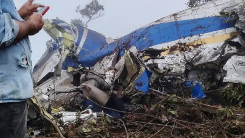 A person stands near the wreckage of a plane crash in Playa de Belen, North Santander, Colombia