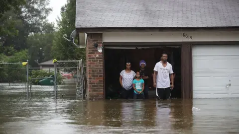 Getty Images A family waiting to be rescued from their flooded home.