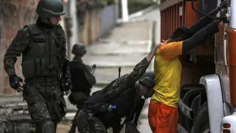 Getty Images Law enforcement officers search a man in Niteroi, in the metropolitan region of Rio de Janeiro, Brazil, 16 August 2017