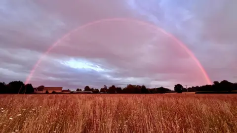 Debbie/Weather Watchers A pink coloured rainbow after a rain shower at sunset in Cirencester. 