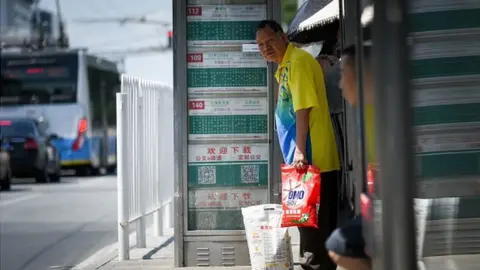 AFP A man waiting for a bus in Beijing
