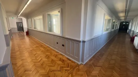 Hallway with wooden floor and grey wood panel walls 