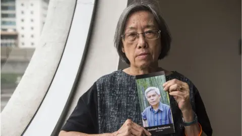 Getty Images Shui Meng Ng holds a picture of her missing husband Sombath Somphone in December 2018