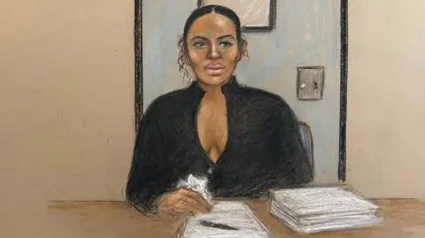 Court sketch of Gabriella Carrington who has pen on a piece of paper next to s stack of papers. She is in front of a blue prison door and is in black