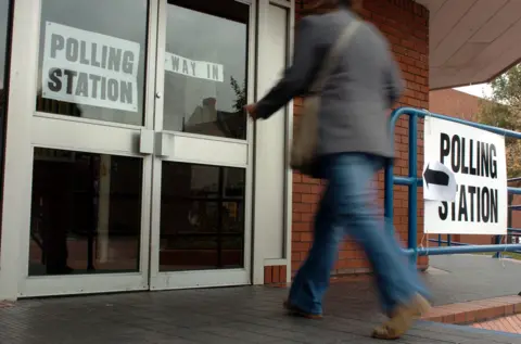 A voter enters double doors signposted with the words "polling station"