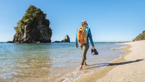 Getty Images A women walks on a beach in the Abel Tasman National Park in New Zealand