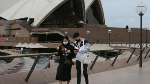 Getty Images People walk along the Sydney Opera House concourse