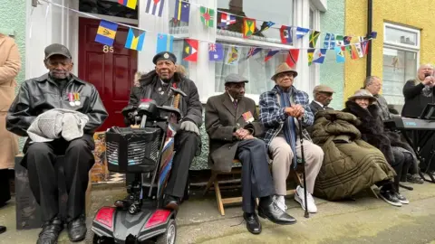 Abi Jaiyeola/BBC People sat outside the house