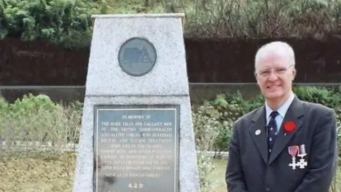 Michael Hurst Michael Hurst standing in front of the memorial at the Kinkaseki memorial camp