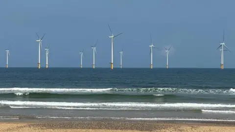 Duncan Leatherdale Wind turbines out at sea pictured from a beach