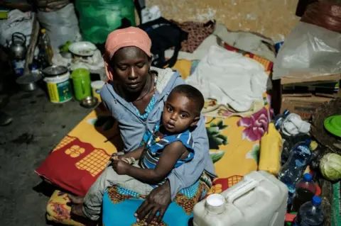 AFP A mother, who fled the violence in Ethiopia's Tigray region, holds her child in a classroom.