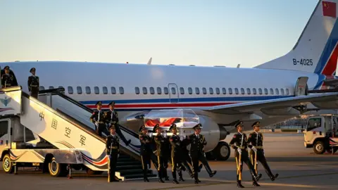 XINHUA Chinese soldiers frogmarch as they carry Jiang Zemin's glass coffin off a place arriving from Shanghai