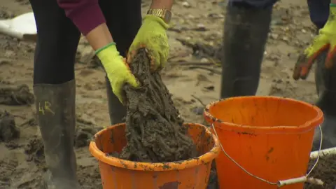 BBC Wet wipes stuck together are pulled from the mud on the bank