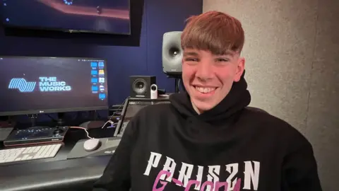 Jayden Gardiner sitting in a chair wearing a hoodie and smiling at the camera