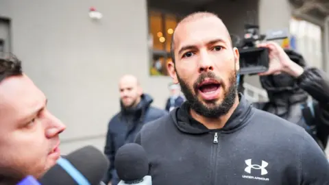 Getty Images Online influencer Andrew Tate surrounded by press