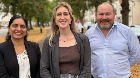 Warwick District Green Party Becky Davidson (pictured centre) with Green councillors Hema YellaPragada and Will Roberts. The three councillors are looking towards the camera and smiling. 