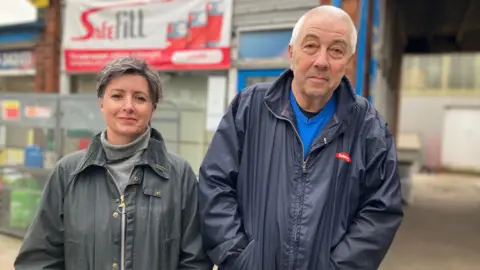 BBC Kerry McNair, wearing a grey turtleneck and grey jacket, stood next to Martin Brass, wearing a blue jumper and navy coat.