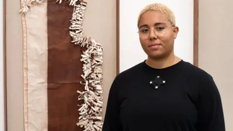 Belinda Lawley Tanoa Sasraku standing next to one of her nominated works in a gallery