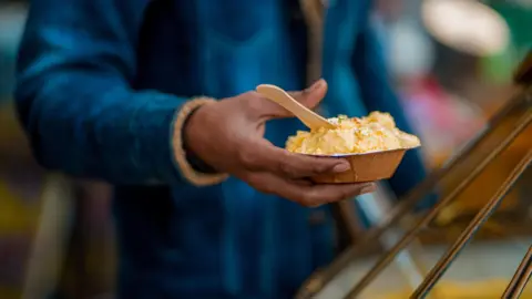 Maroof Culmen A man's hand holds a plate of dessert in Lucknow