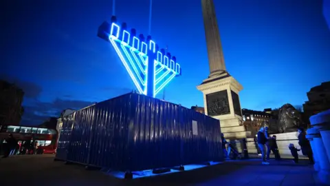 James Manning/PA Wire A large menorah lit-up in neon light stands in Trafalgar Square, in front of Nelson's Column, as night falls