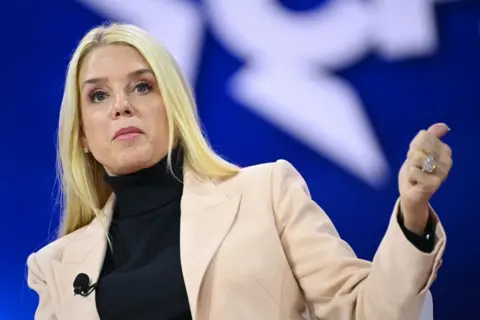 Getty Images Pam Bondi speaks during the annual Conservative Political Action Conference in Maryland in February. She has straight, blonde hair and wears a light beige blazer and a black turtleneck.