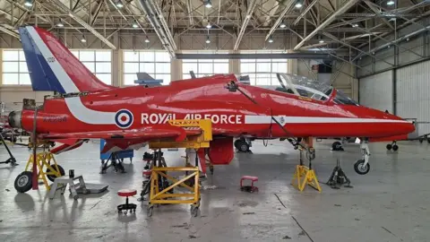 RAF Cosford Museum A British Aerospace Hawk T1A, with red, white and blue livery, is parked in an aircraft hangar. It has Royal Air Force in white letters on the side