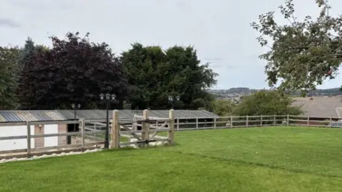 A GV of a field and dog kennels with a fence 