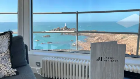 View from inside lookout tower towards rocks, sea and lighthouse.