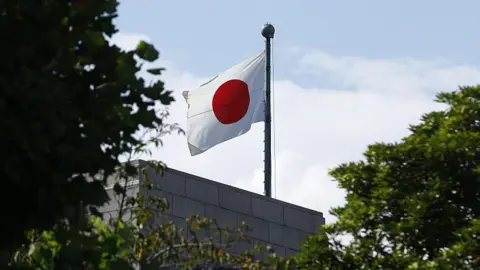 A Japanese flag is visible through trees