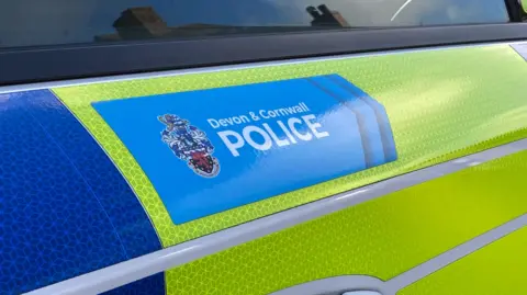 A police car with a blue Devon and Cornwall Police logo. It's a blue and green police car.