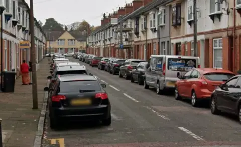 Google Cars parked on either side of a terraced street, flanked by houses on either side.