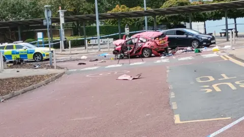 @GrantTheHatter Mangled wreckage of reddish  car   surrounded with debris (middle) and constabulary  car   (left) with a achromatic  car   down  the crashed one