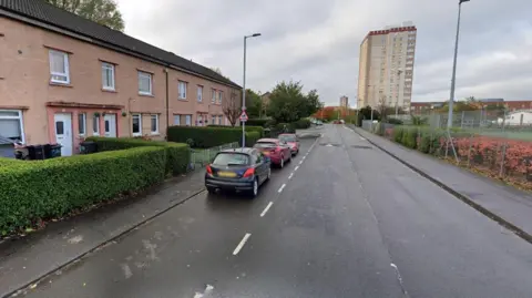 Roads and houses on West Pilton Street. There is a block of high-rise flats in the distance.