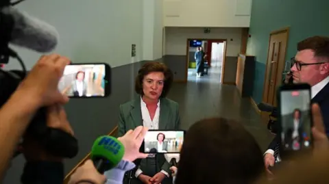 Getty Images Eluned Morgan speaks to media after losing her seat - news crews and journalists filming with mobile phones as she stands in the hall