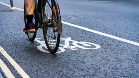 Someone riding a black bike in a cycle lane.