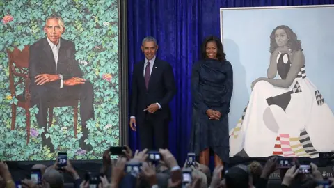 Barack and Michelle Obama pose with their portraits